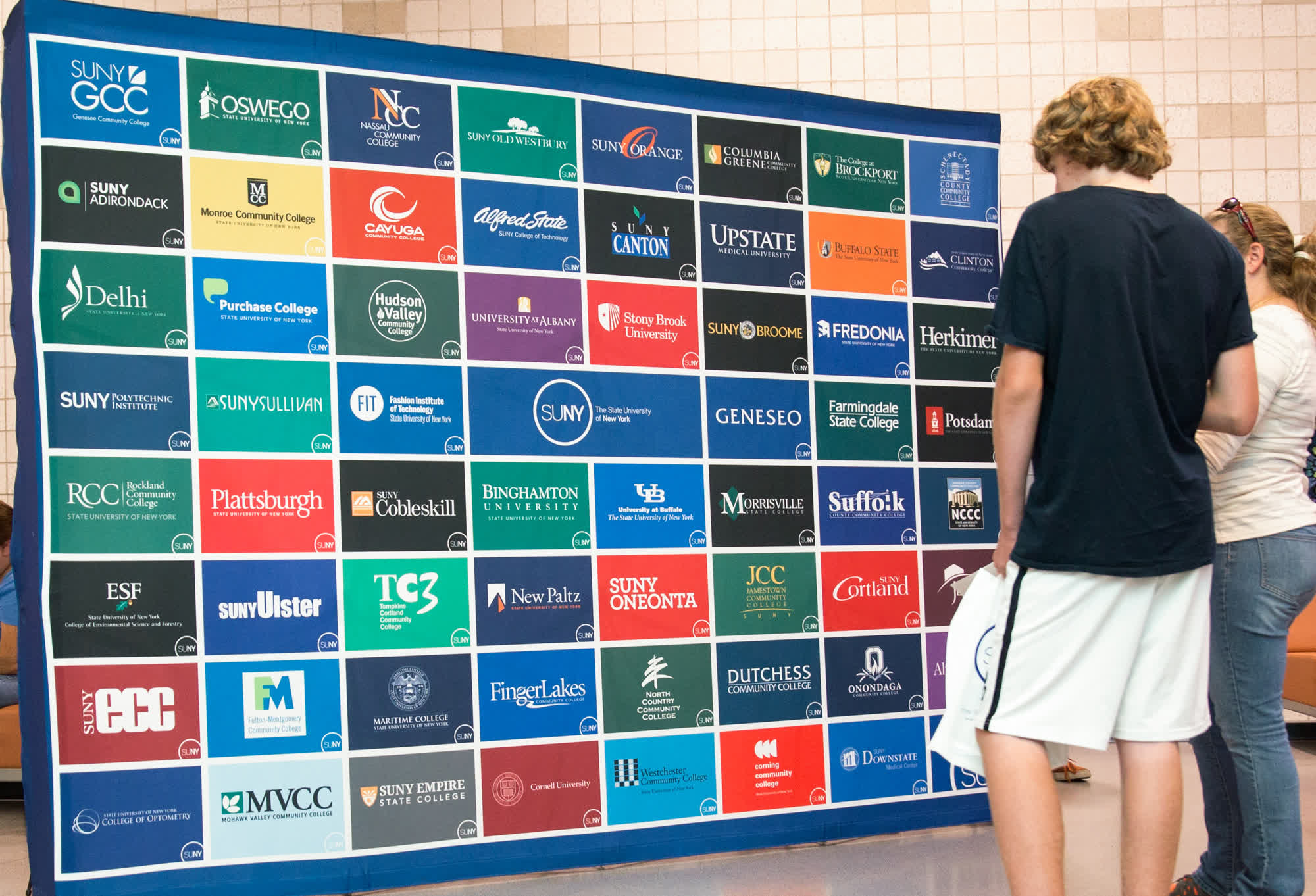 Rows of SUNY campus banners at a college fair.